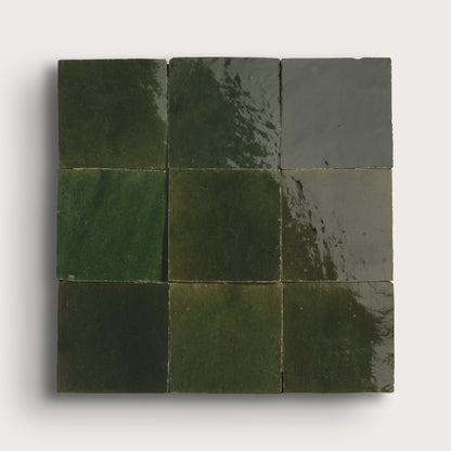 Nine square zellige tiles in various shades of green on a white background