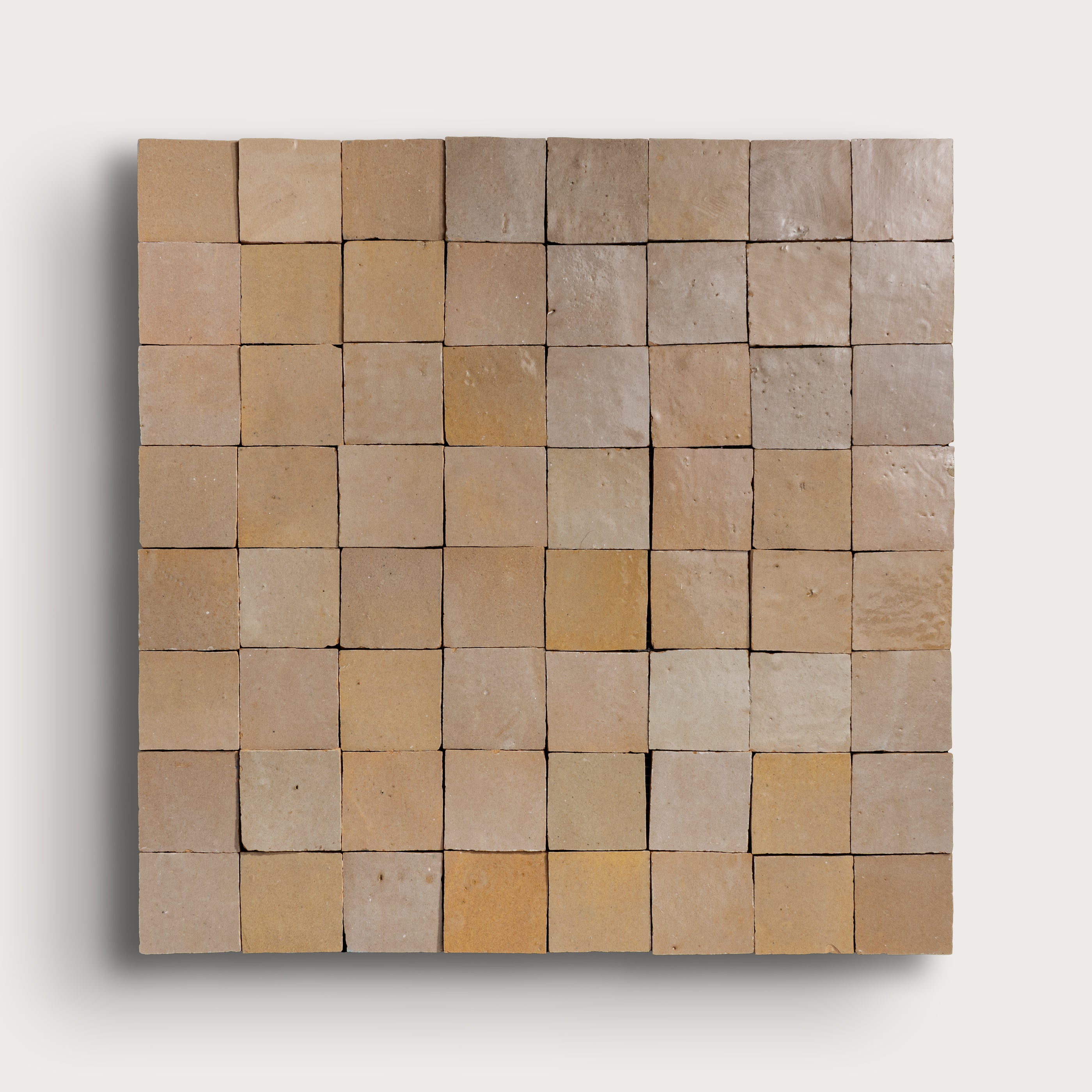Square arrangement of square tiles in various beige tones on a white background