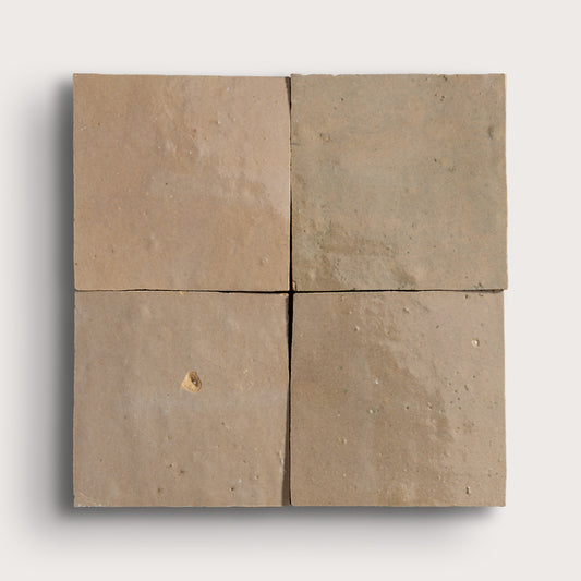 Brown square zellige tile with a small chip on a white background