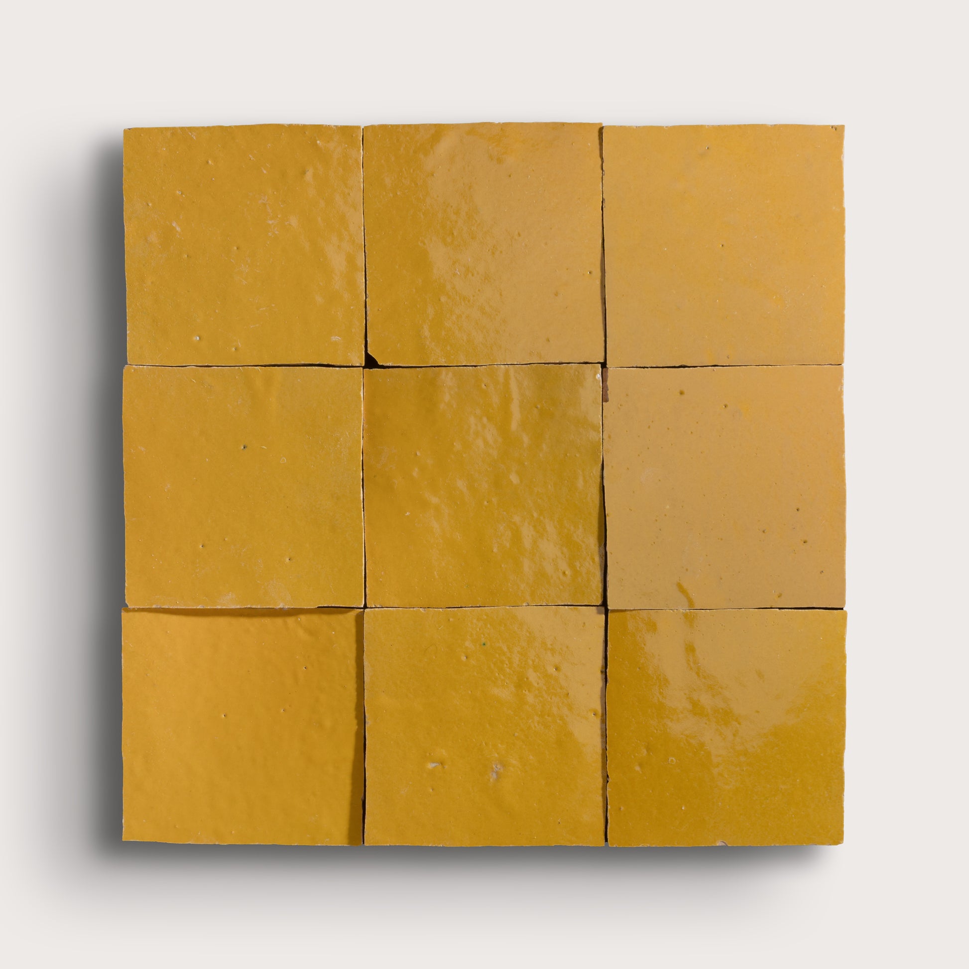 Nine square yellow zellige tiles arranged in a 3x3 grid on a white background
