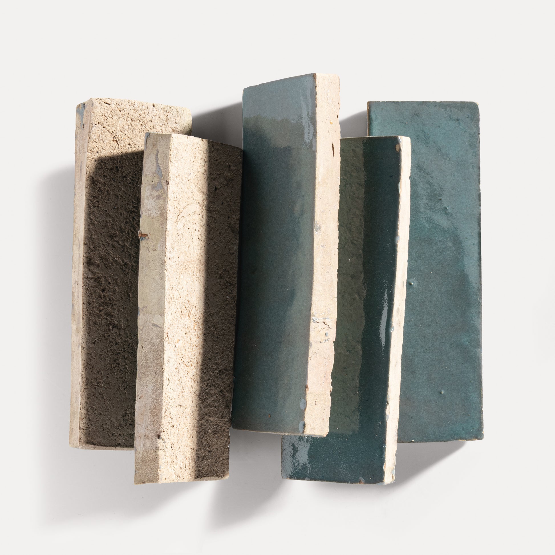 Three rectangular zellige tiles with varying textures and colors on a white background