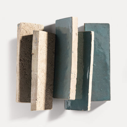 Three rectangular zellige tiles with varying textures and colors on a white background