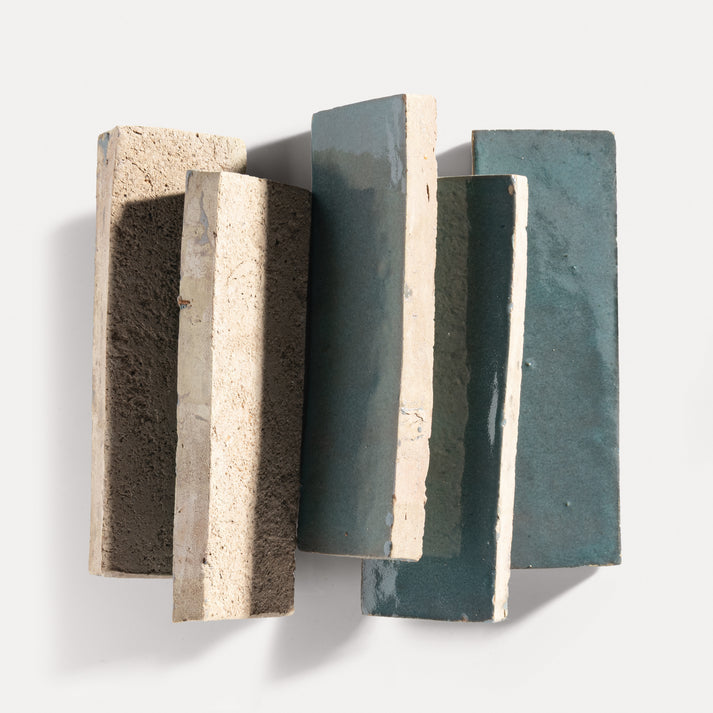 Three rectangular zellige tiles with varying textures and colors on a white background