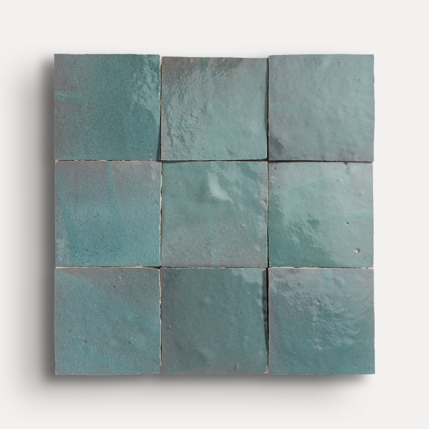 Nine square teal zellige tiles arranged in a grid pattern on a white background
