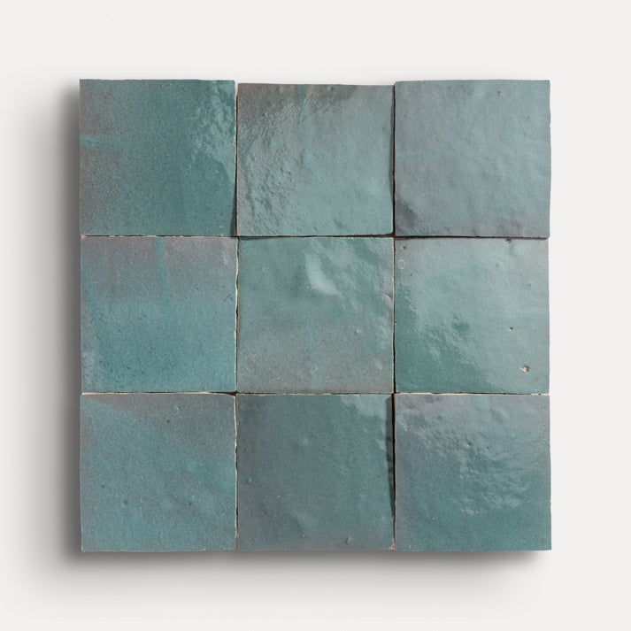 Nine square teal zellige tiles arranged in a grid pattern on a white background
