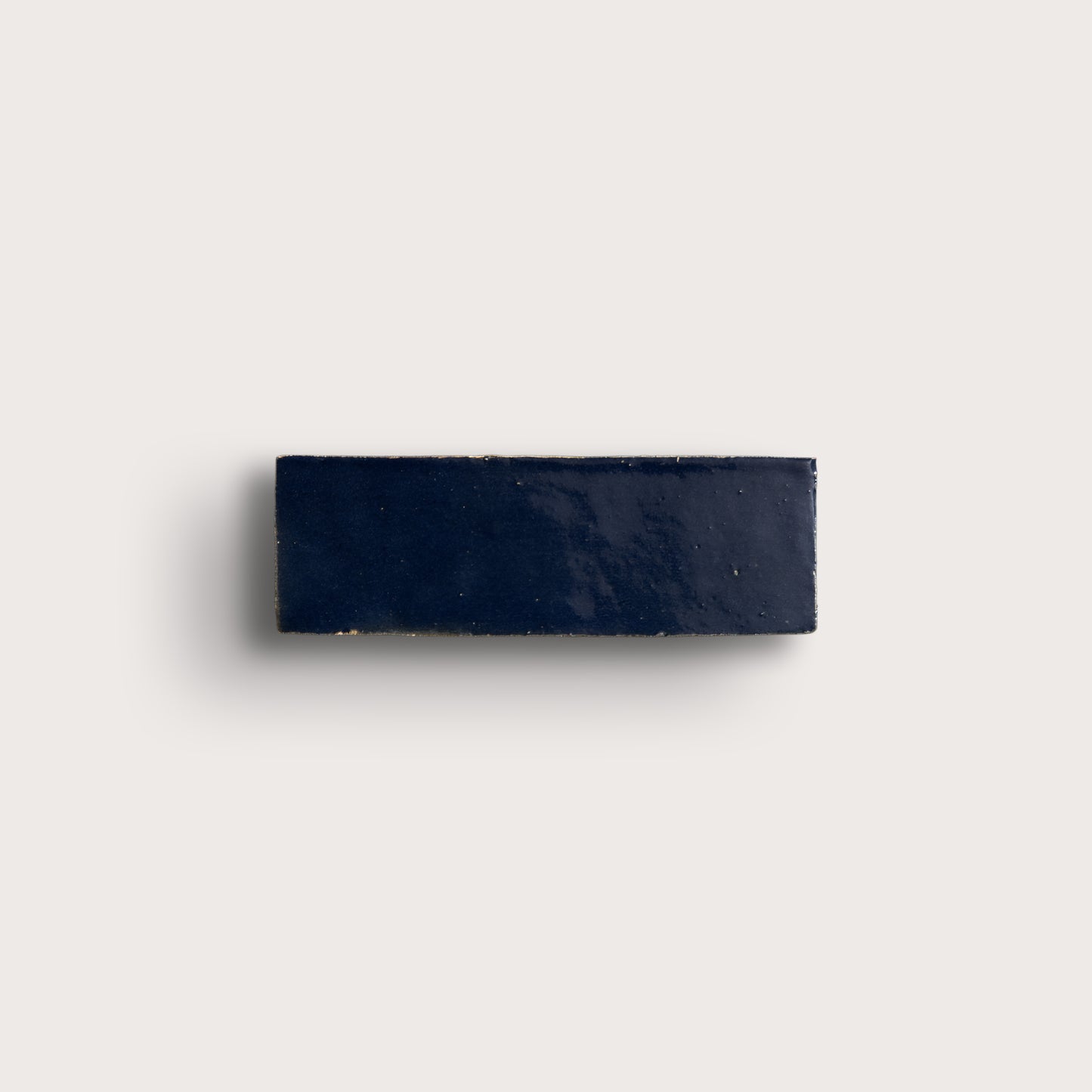 Navy blue rectangular zellige tile on a light gray background