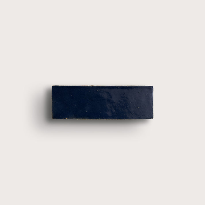 Navy blue rectangular zellige tile on a light gray background