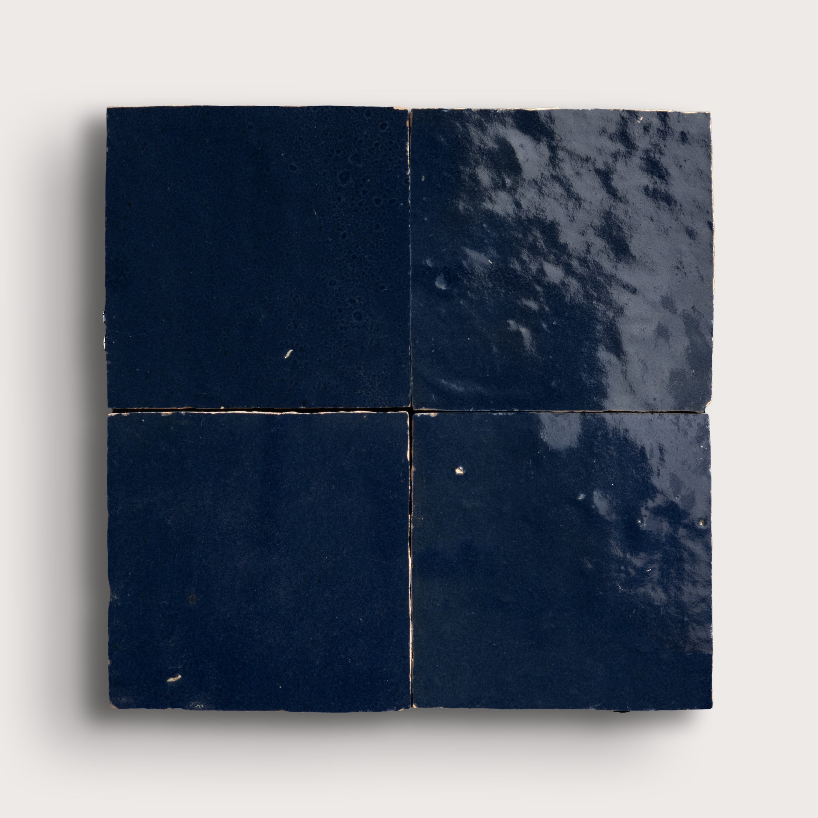 Four dark blue zellige tiles on a white background