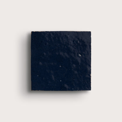 Square piece of dark blue stone on a light gray background