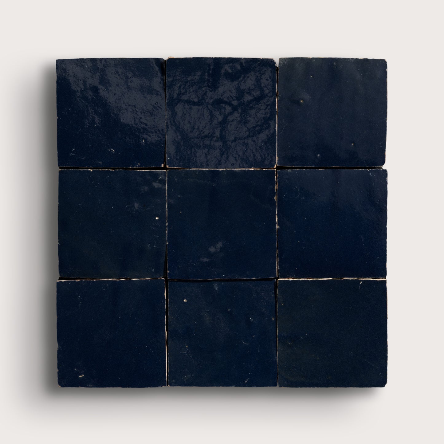 Nine dark blue square zellige tiles arranged in a 3x3 grid on a light gray background