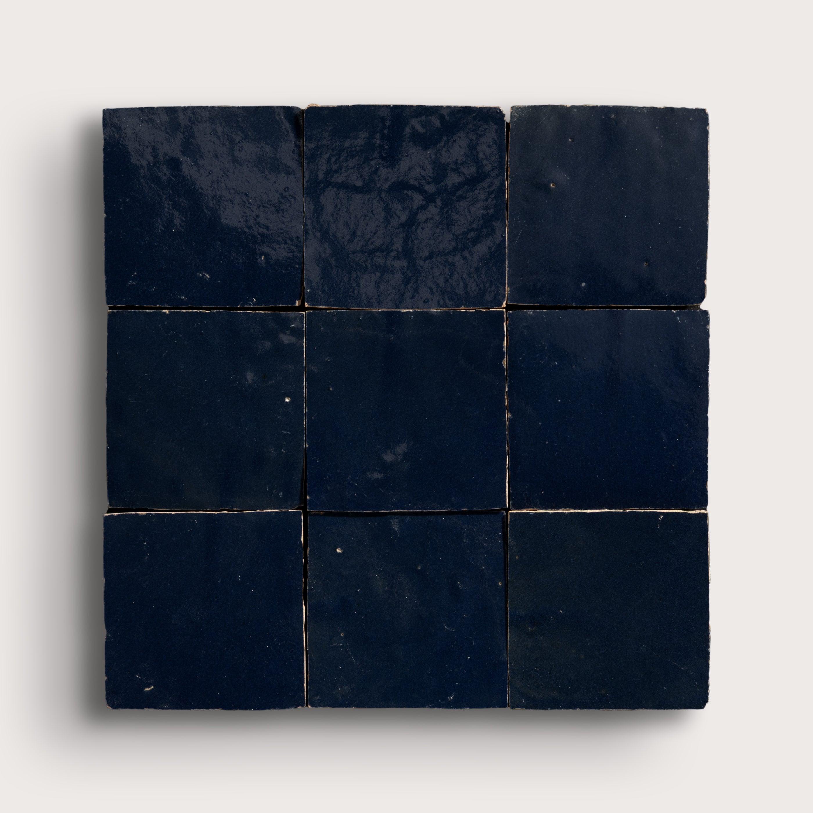 Nine dark blue square zellige tiles arranged in a 3x3 grid on a light gray background