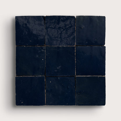 Nine dark blue square zellige tiles arranged in a 3x3 grid on a light gray background