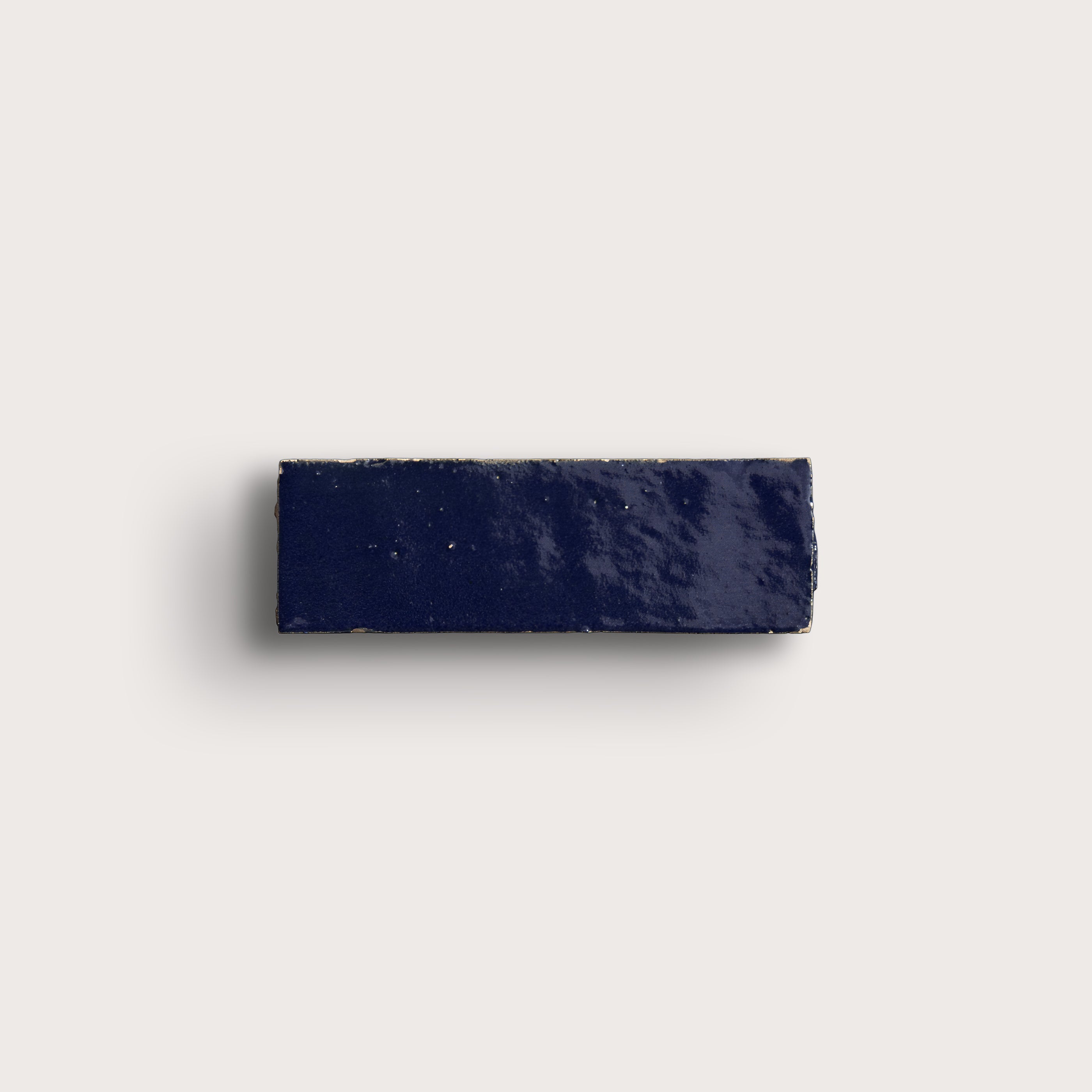 Navy blue rectangular zellige tile on a light gray background