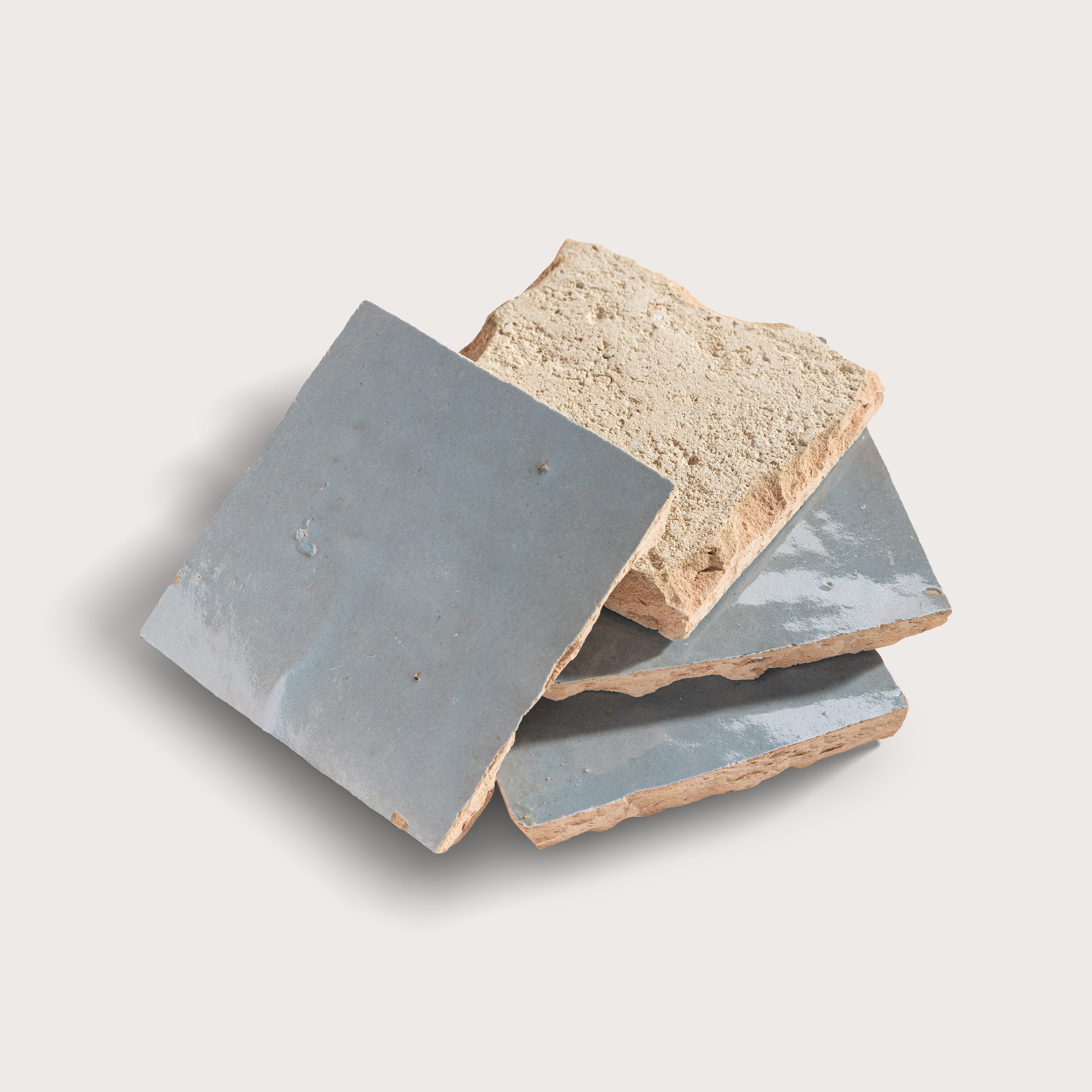 Three zellige tiles with grayish-blue and beige colors on a light gray background