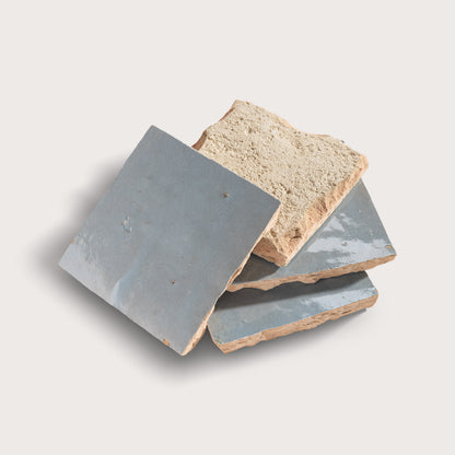 Three zellige tiles with grayish-blue and beige colors on a light gray background