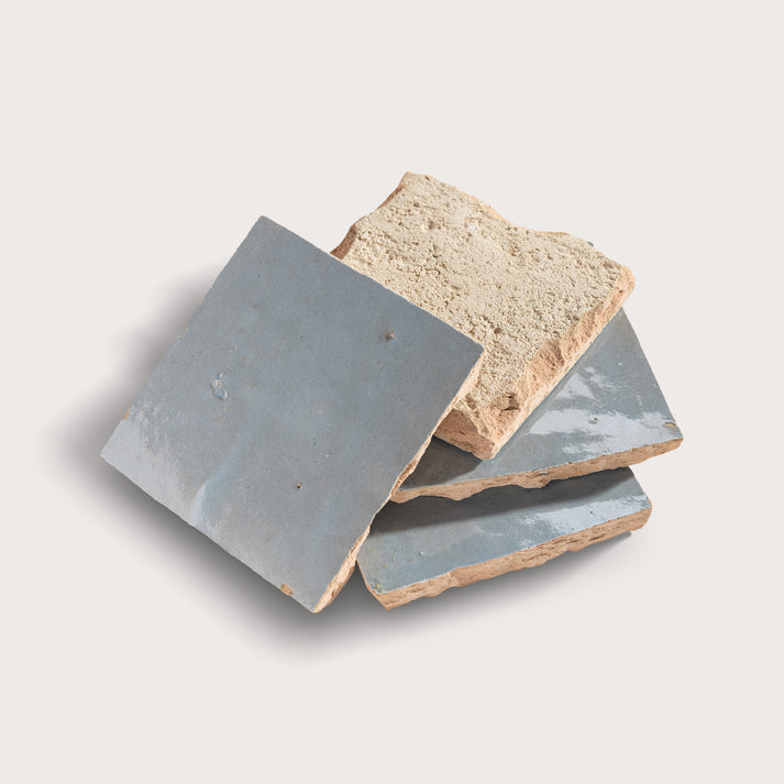 Three zellige tiles with grayish-blue and beige colors on a light gray background