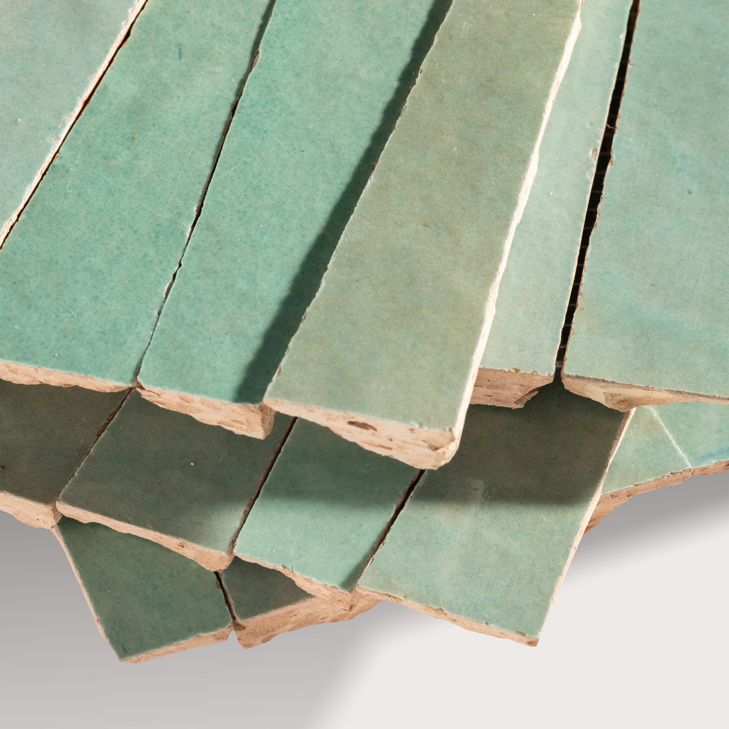 Stack of green zellige tiles with a white background