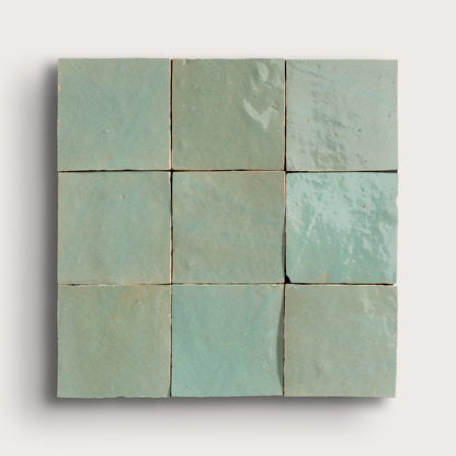A 3x3 grid of square zellige tiles in a light mint green glaze, arranged in a square block with a subtle drop shadow on a light gray background.