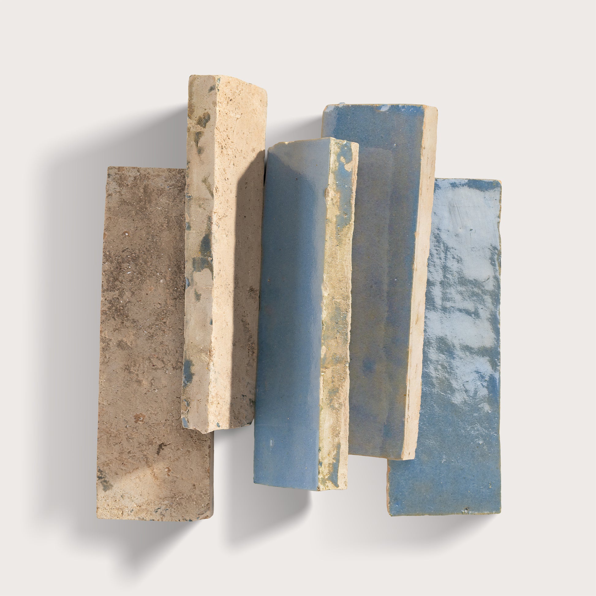 Stack of textured zellige tile with different colors on a white background