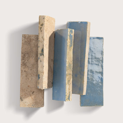Stack of textured zellige tile with different colors on a white background