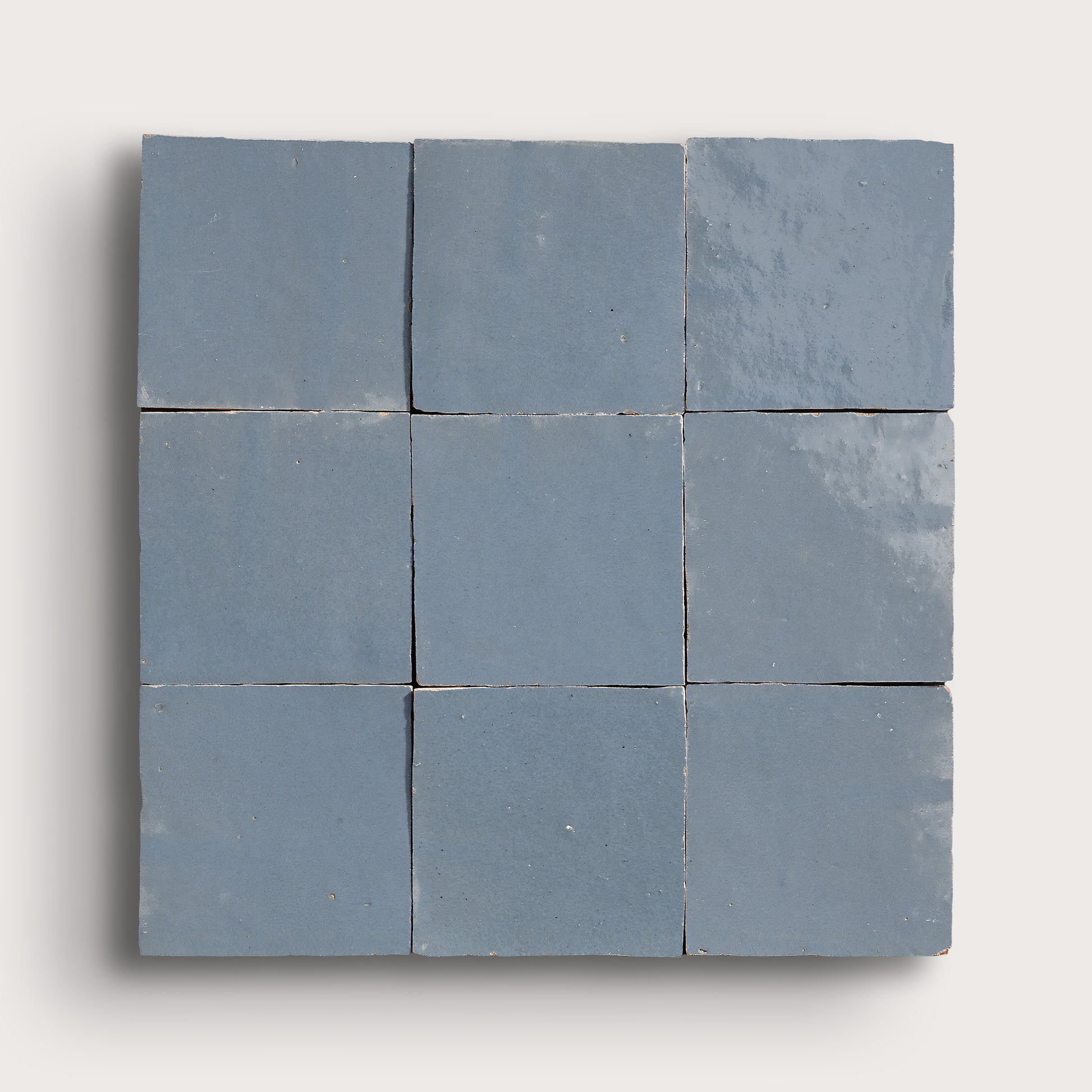 Nine square blue zellige tiles arranged in a 3x3 grid on a white background