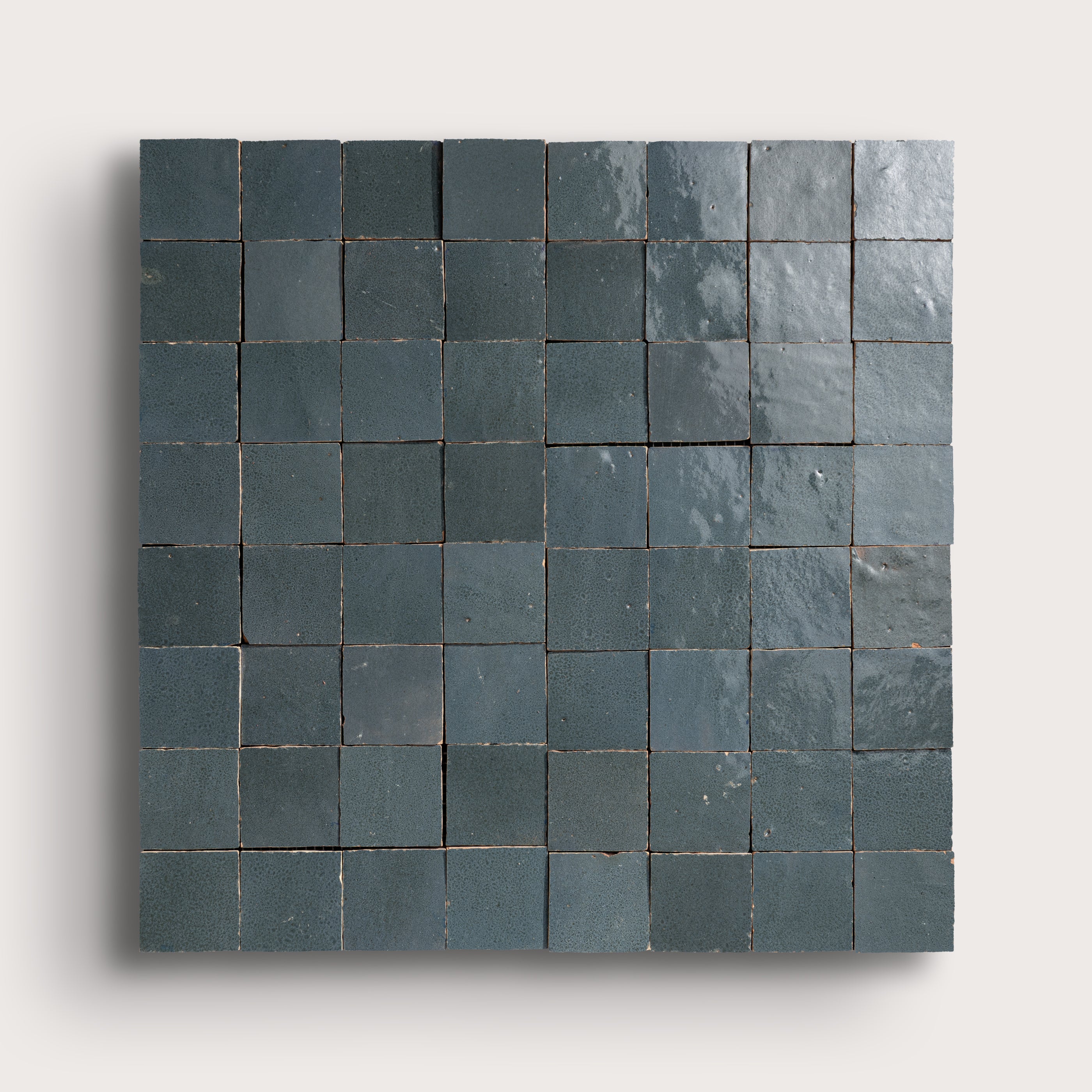Square arrangement of dark gray zellige tiles on a light gray background