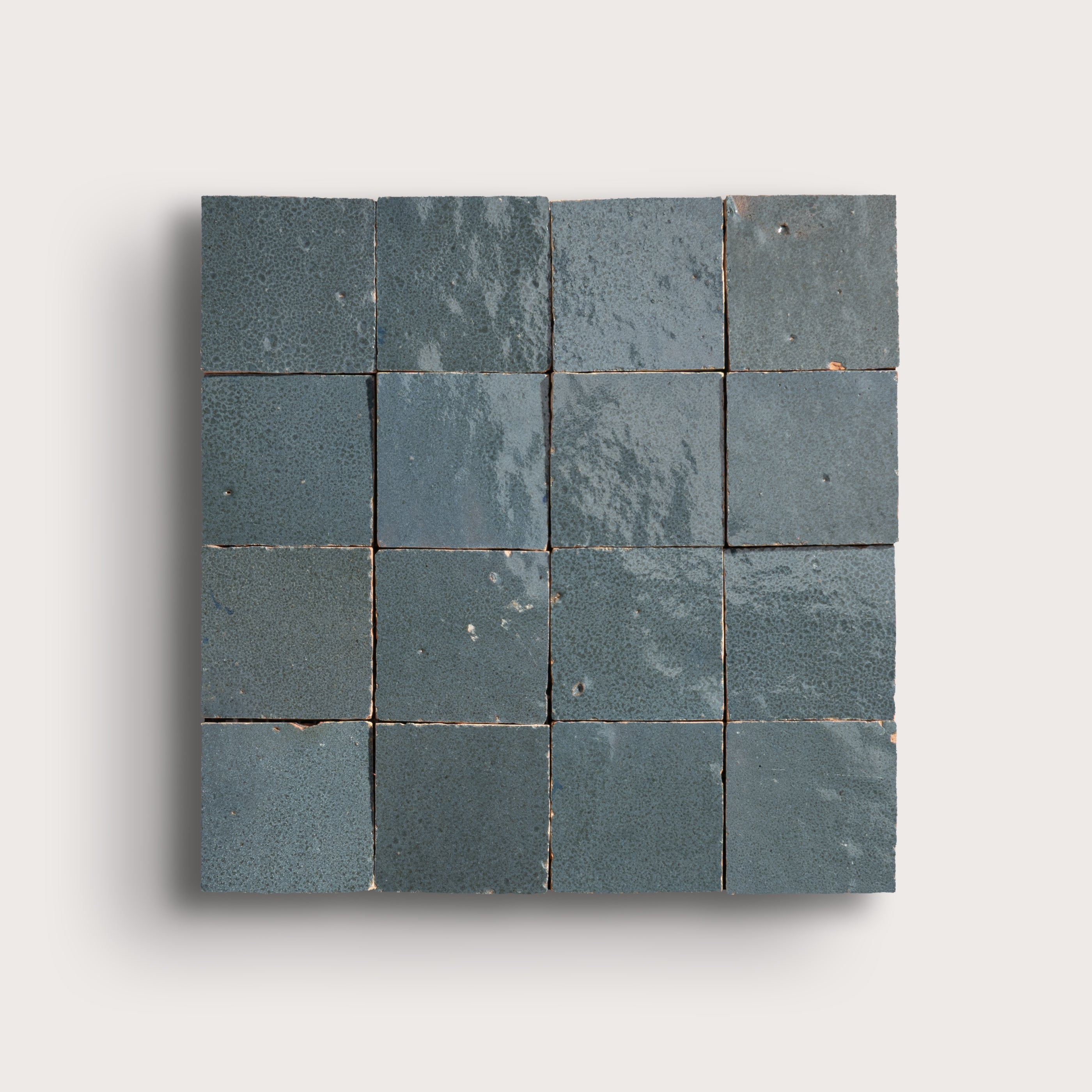 Square arrangement of dark gray zellige tiles on a light gray background