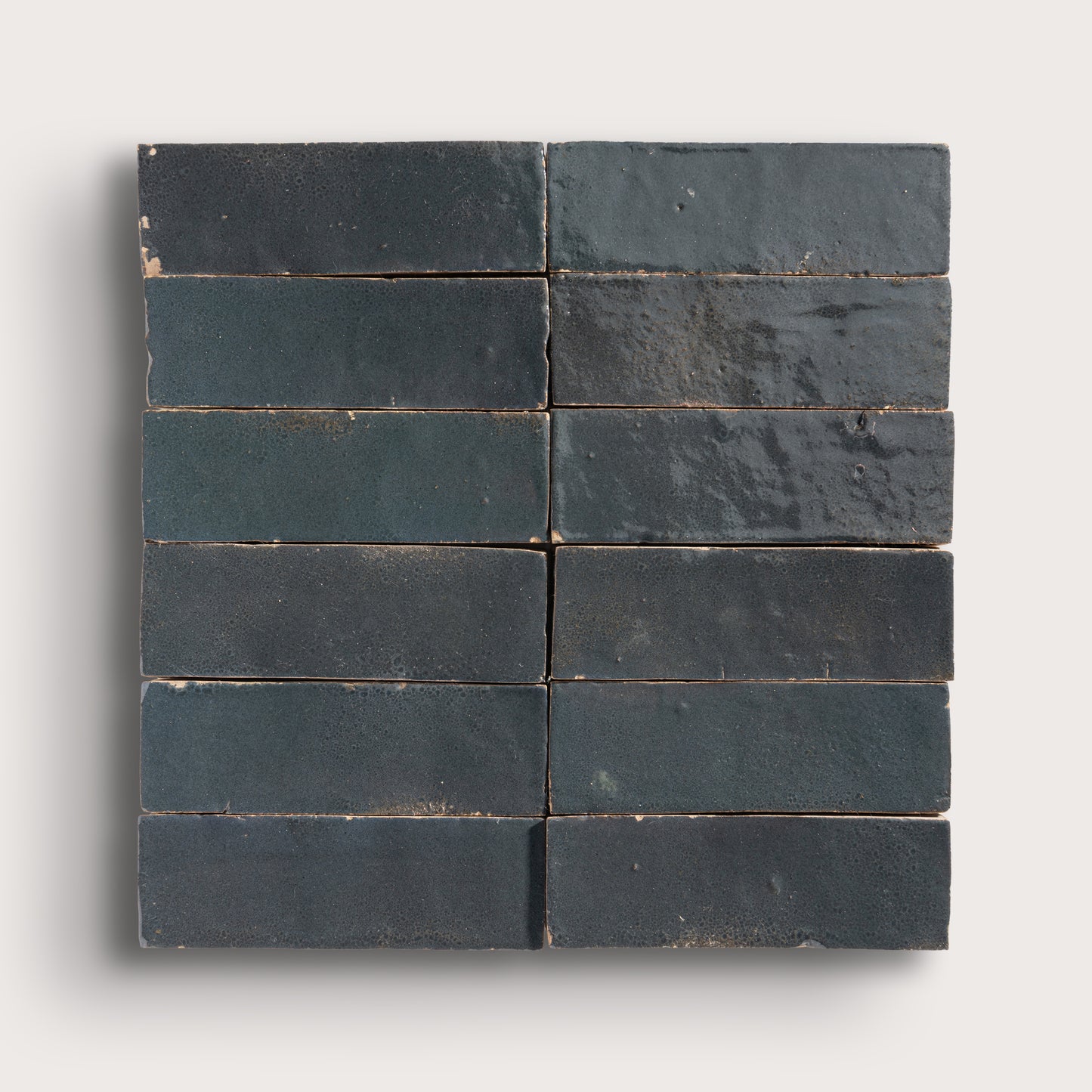 twelve dark gray rectangular zellige tiles arranged in a grid on a light gray background