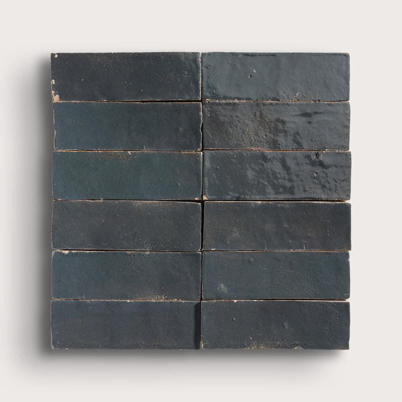 twelve dark gray rectangular zellige tiles arranged in a grid on a light gray background