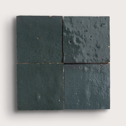 Four grey zellige tiles arranged in a 2x2 grid on a light gray background