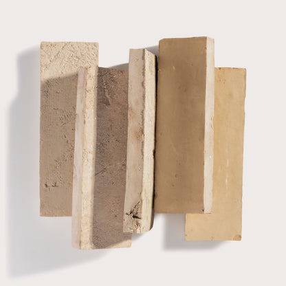 Five rectangular textured zelige tile in neutral beige, tan, and light brown tones, arranged in a staggered vertical stack against a clean off-white background.