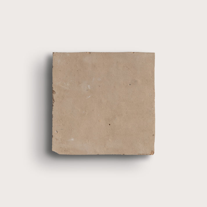 A square beige zellige tile with a rough, natural texture, shown against a light gray background with a soft drop shadow.