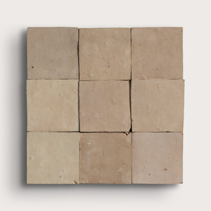 A 3x3 grid of square zellige tiles in varying shades of beige and light brown, arranged in a square formation against a light gray background.