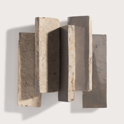 A set of five textured rectangular zellige wall tiles in neutral earthy tones, arranged in a staggered vertical pattern against a light gray background.