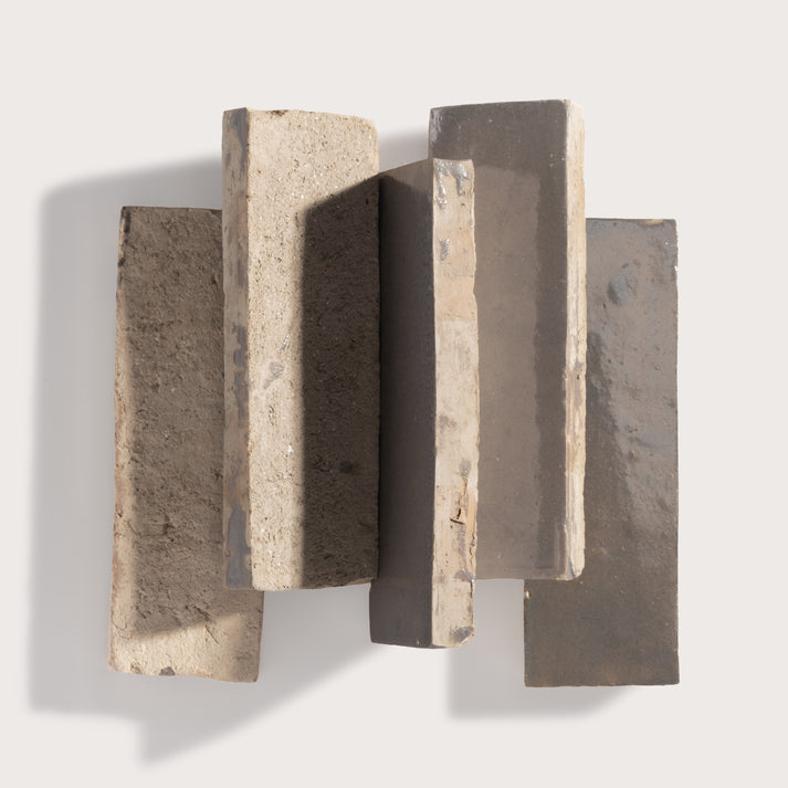 A set of five textured rectangular zellige wall tiles in neutral earthy tones, arranged in a staggered vertical pattern against a light gray background.