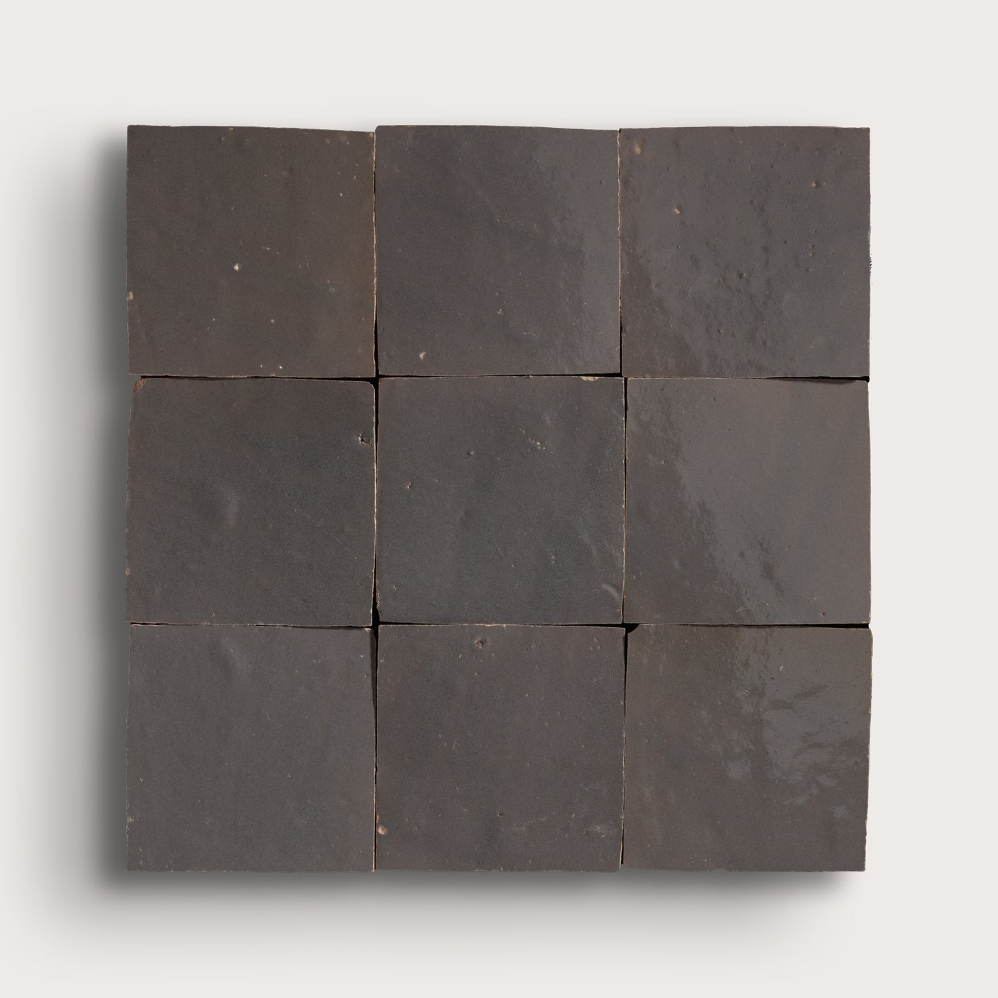 A 3x3 grid of dark charcoal gray square tiles arranged in a square panel, shown against a light gray background.