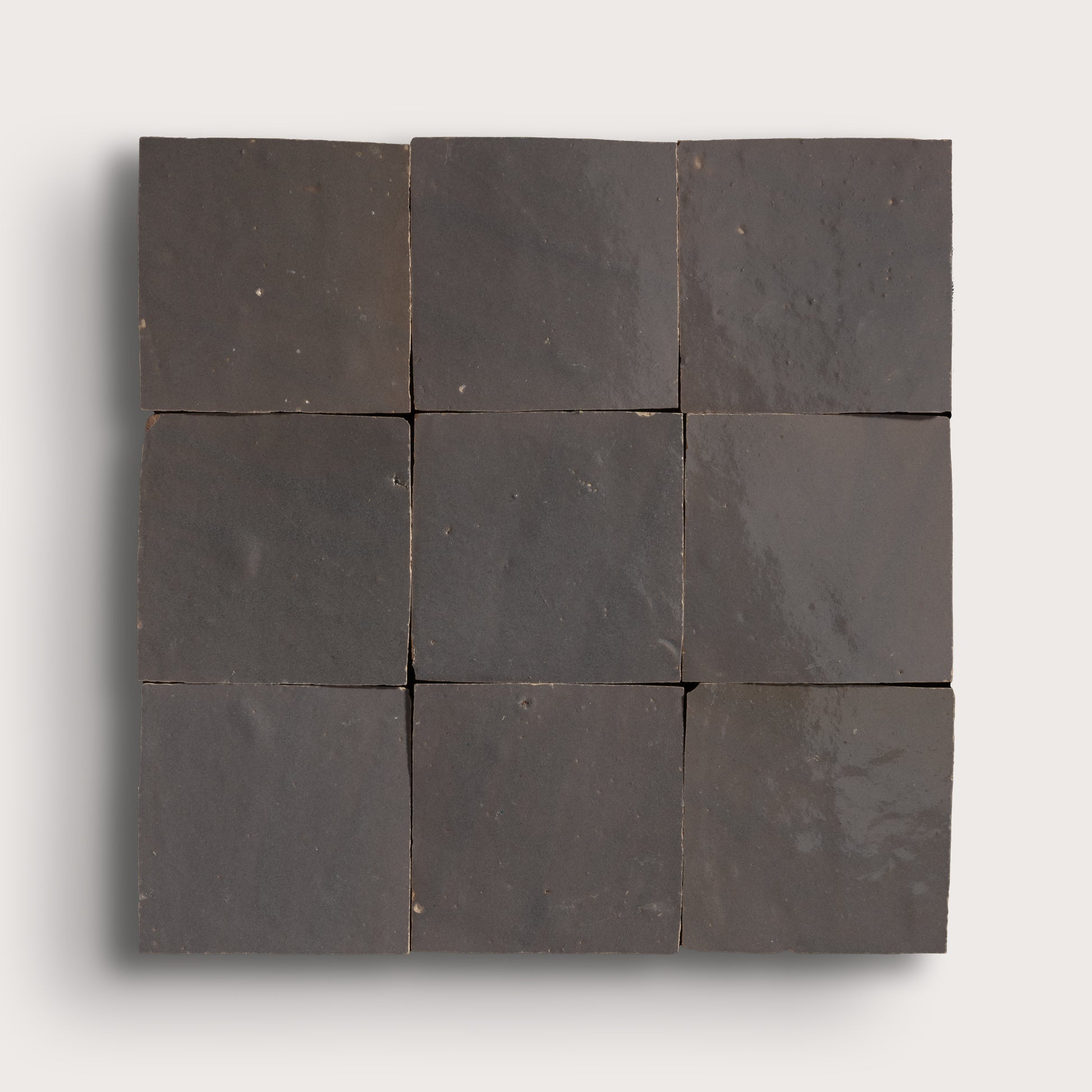 A 3x3 grid of dark charcoal gray square tiles arranged in a square panel, shown against a light gray background.