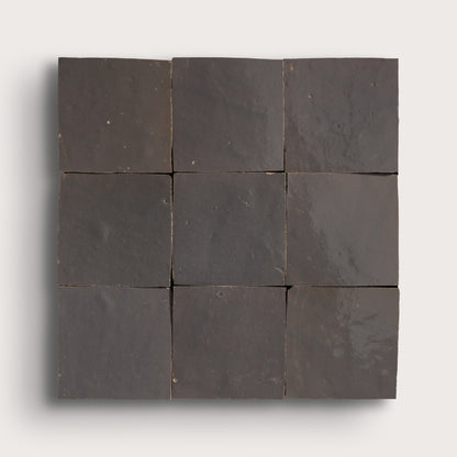 A 3x3 grid of dark charcoal gray square tiles arranged in a square panel, shown against a light gray background.