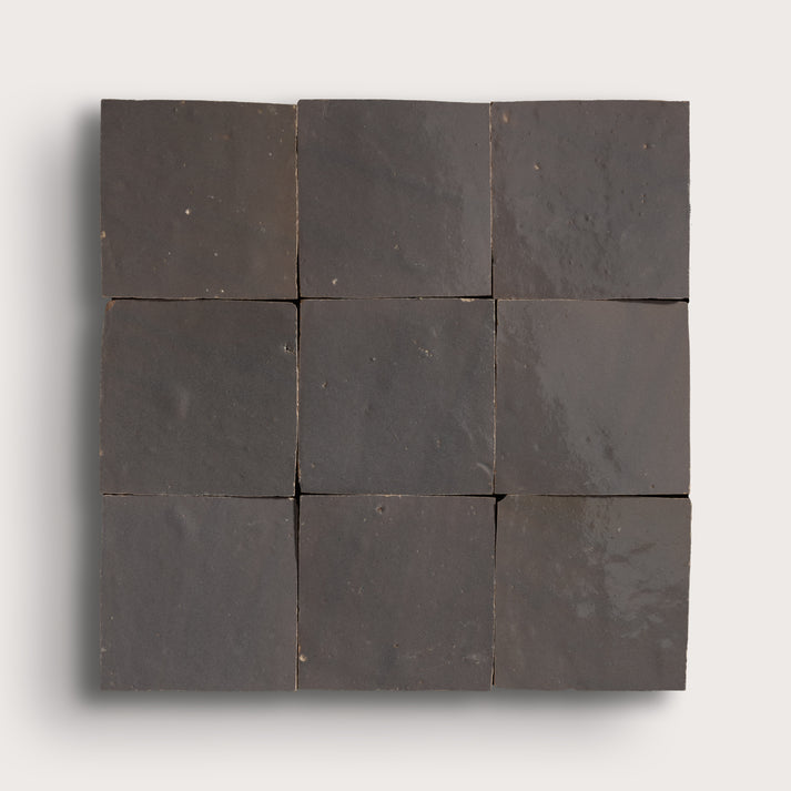 A 3x3 grid of dark charcoal gray square tiles arranged in a square panel, shown against a light gray background.