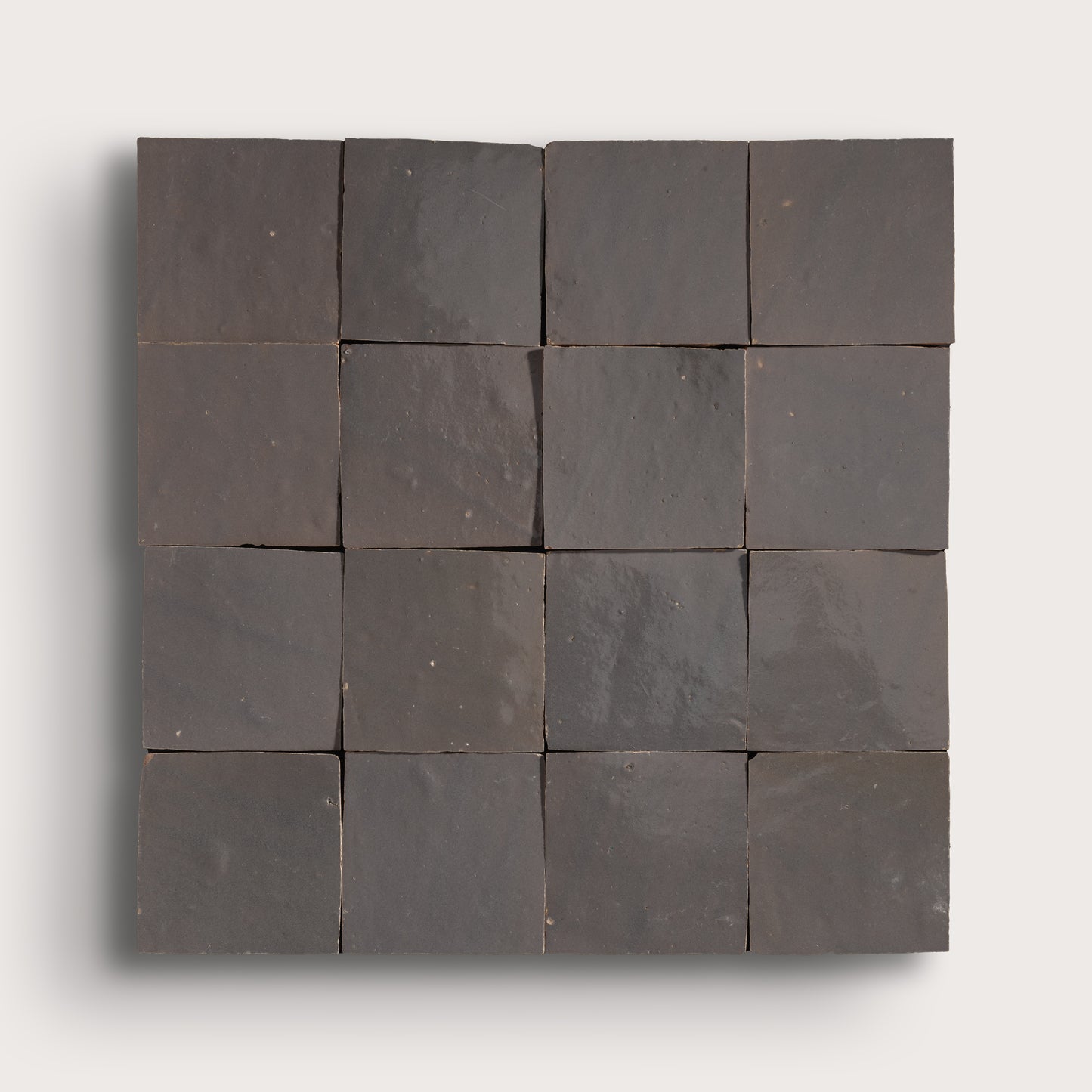 A square arrangement of dark charcoal gray stone tiles with a matte, textured finish, displayed on a light gray background.