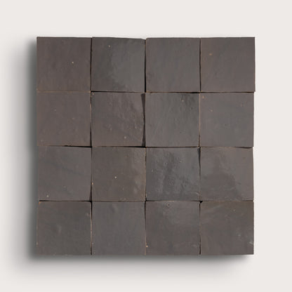 A square arrangement of dark charcoal gray stone tiles with a matte, textured finish, displayed on a light gray background.