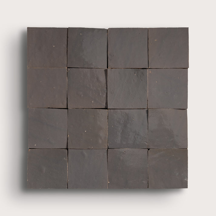 A square arrangement of dark charcoal gray stone tiles with a matte, textured finish, displayed on a light gray background.