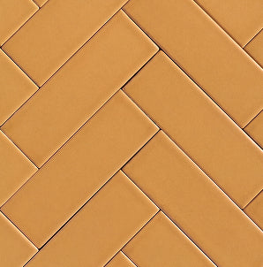 Terracotta brown rectangular ceramic tiles arranged in a herringbone pattern, filling the entire frame.