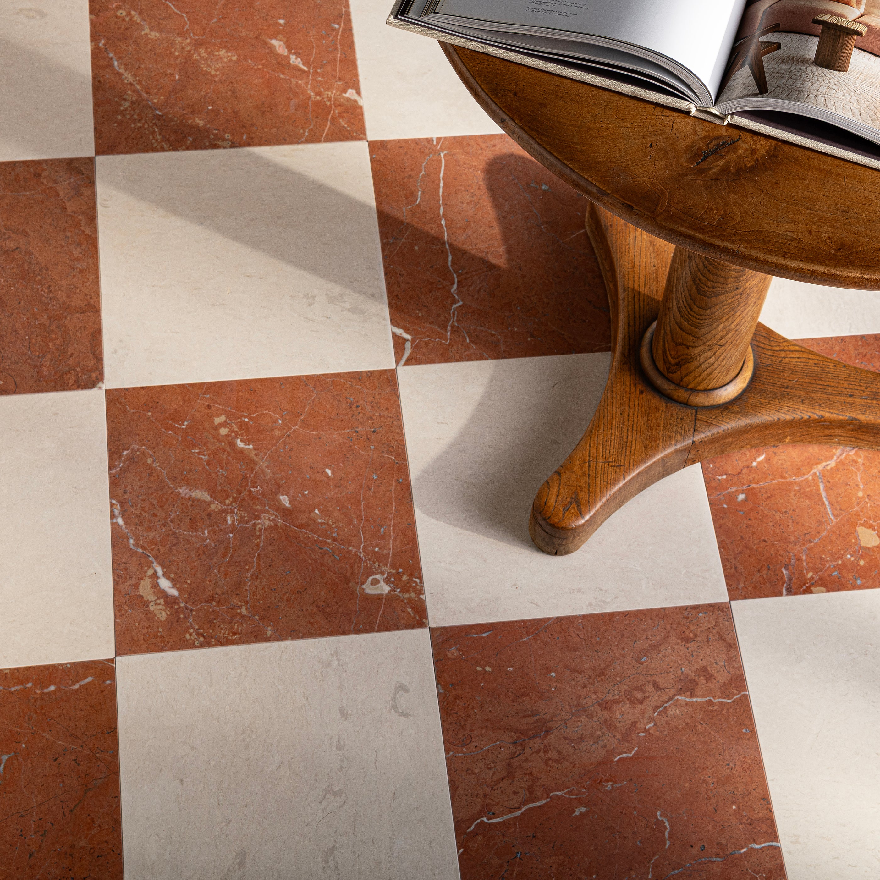 Wooden table on a checkered floor with red marble and white limestone tiles