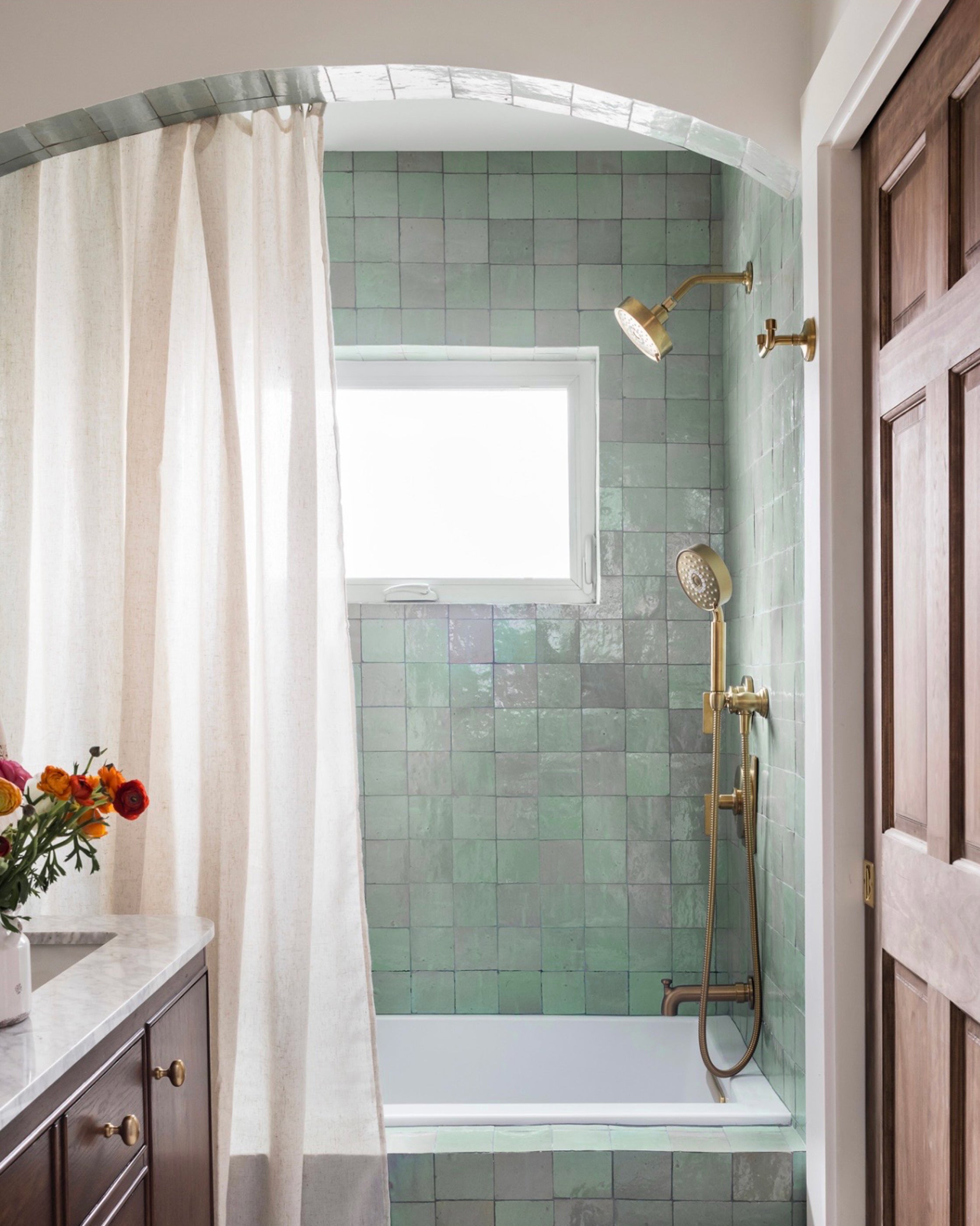 Bathroom with green zellige tiled shower and brass fixtures