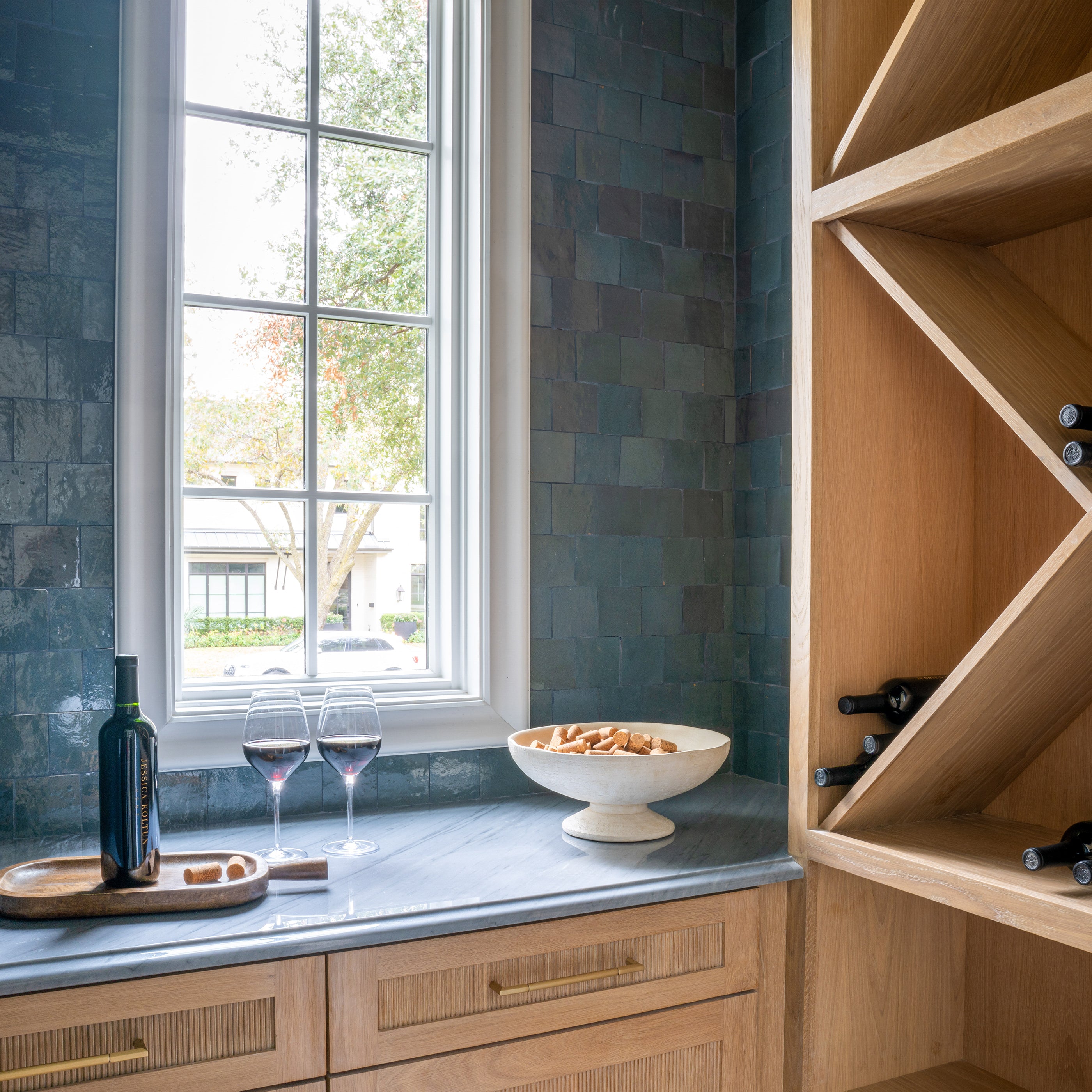 Modern kitchen with wooden shelves, a window, and grey and blue zellige backsplash tile.