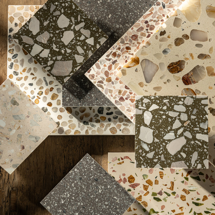 Collection of terrazzo tiles with various patterns and colors on a wooden surface.