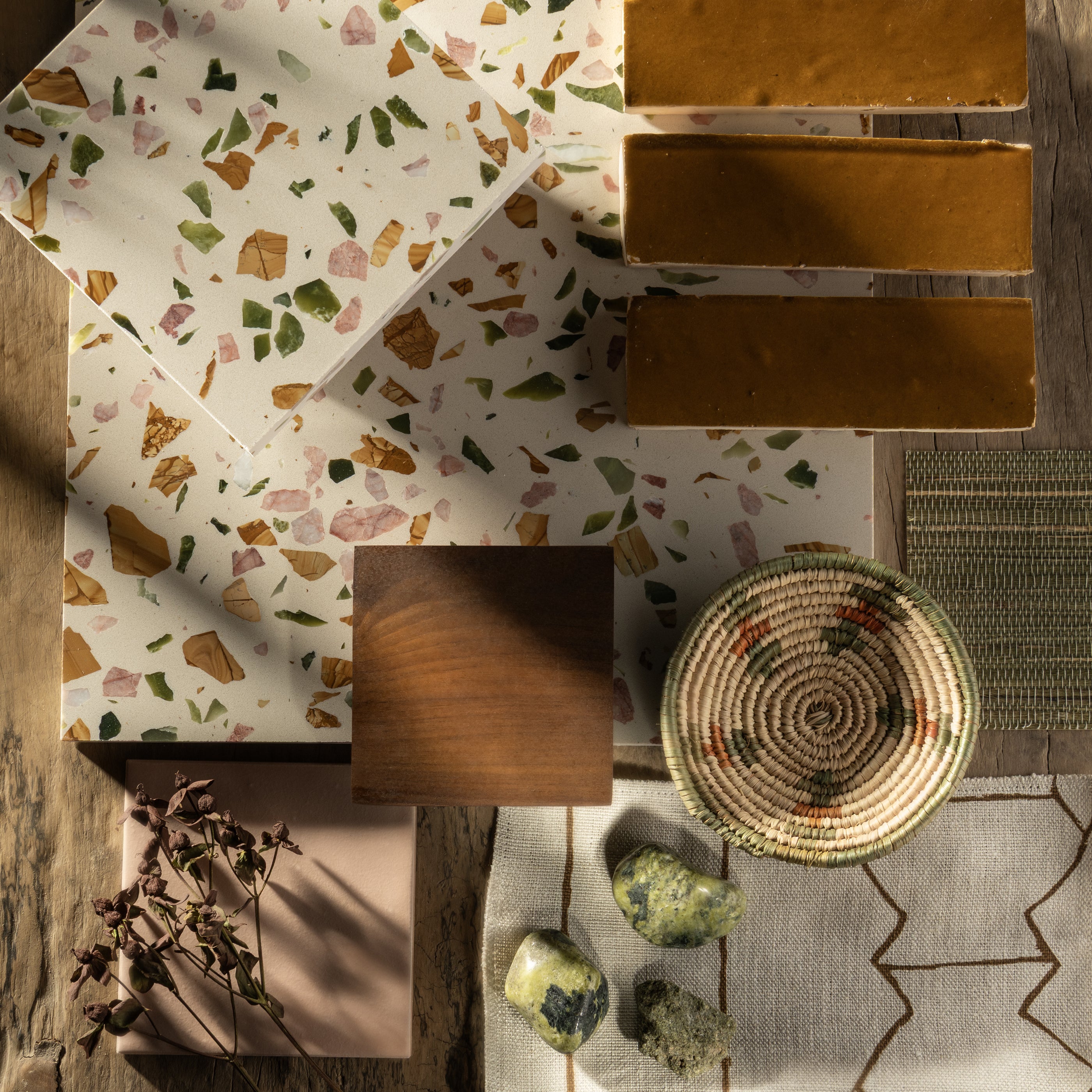 Collection of terrazzo tiles with various patterns and colors on a wooden surface.