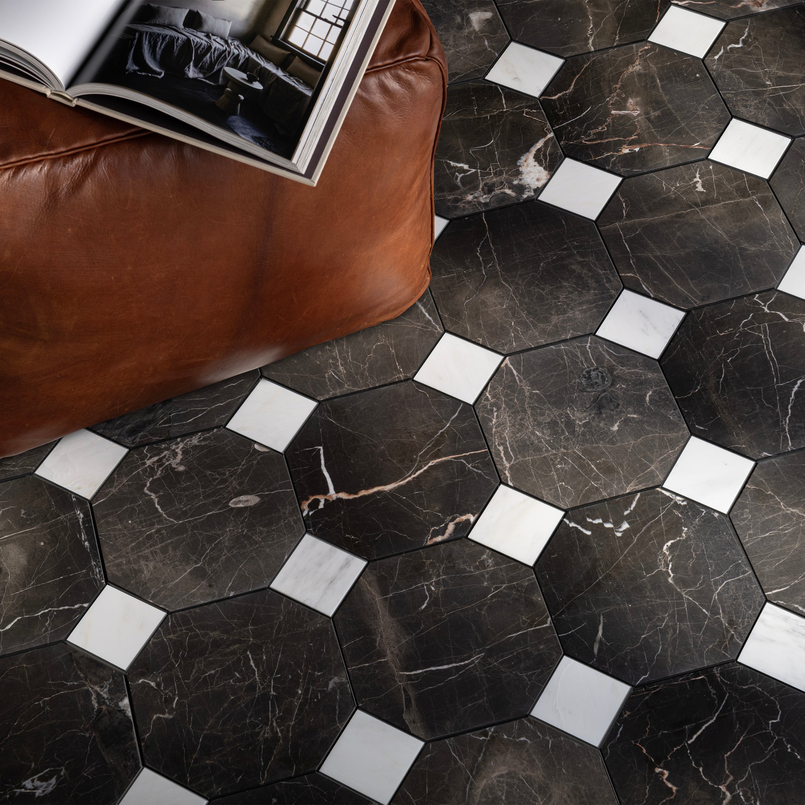 Hexagonal black marble tiles with white accents on a floor next to a brown leather couch.