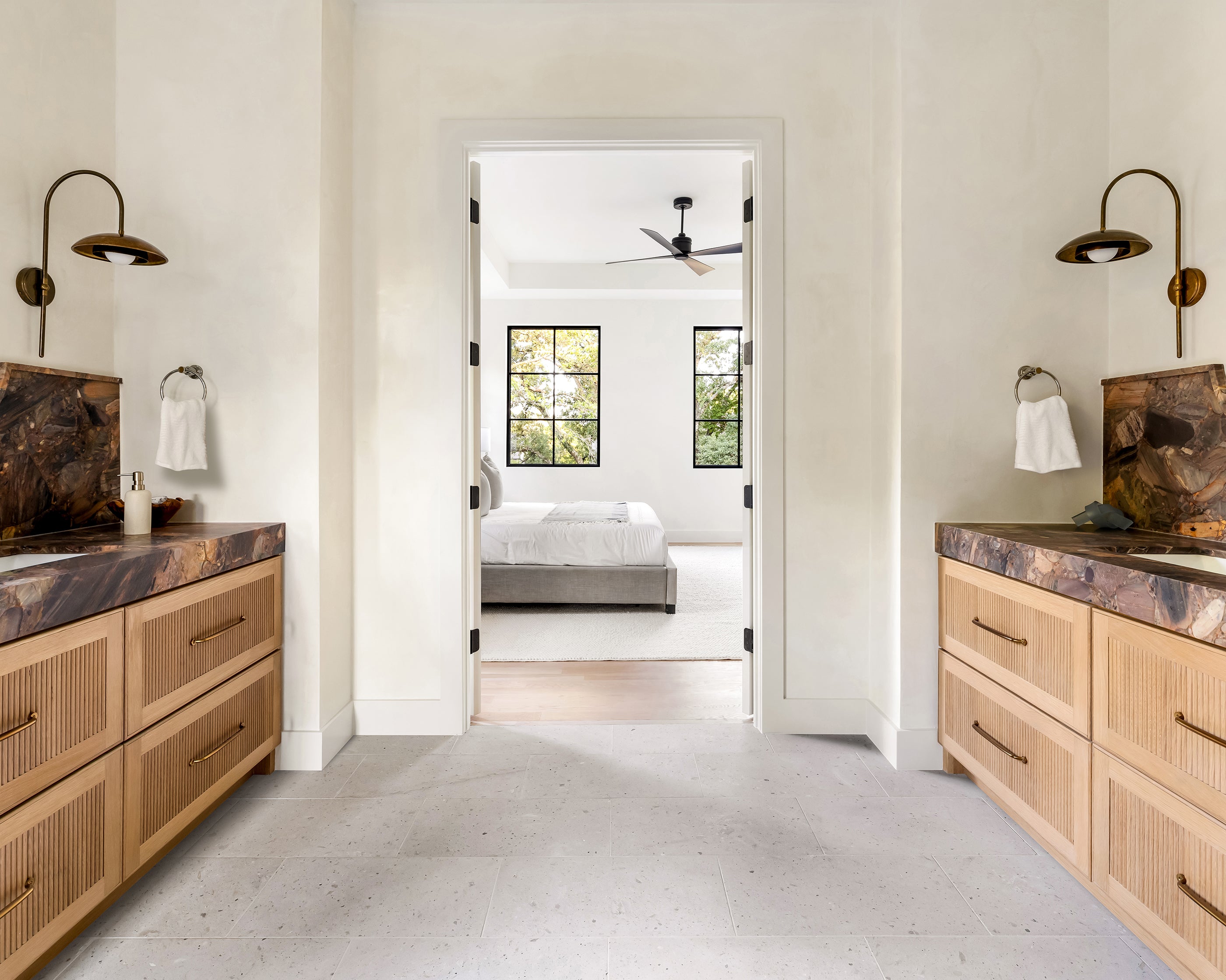 Modern bathroom with wooden cabinets, marble countertops, terrazzo flooring, and a view into a bedroom.